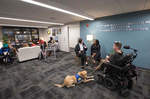 Students in the Miller center for Student Disabiility Services and one yellow lab service dog