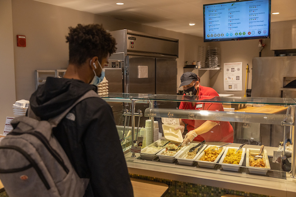 Photo of dining services employee serving a Miami student