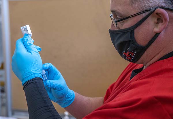 A man with a Miami face mask prepares a needle for covid vaccination