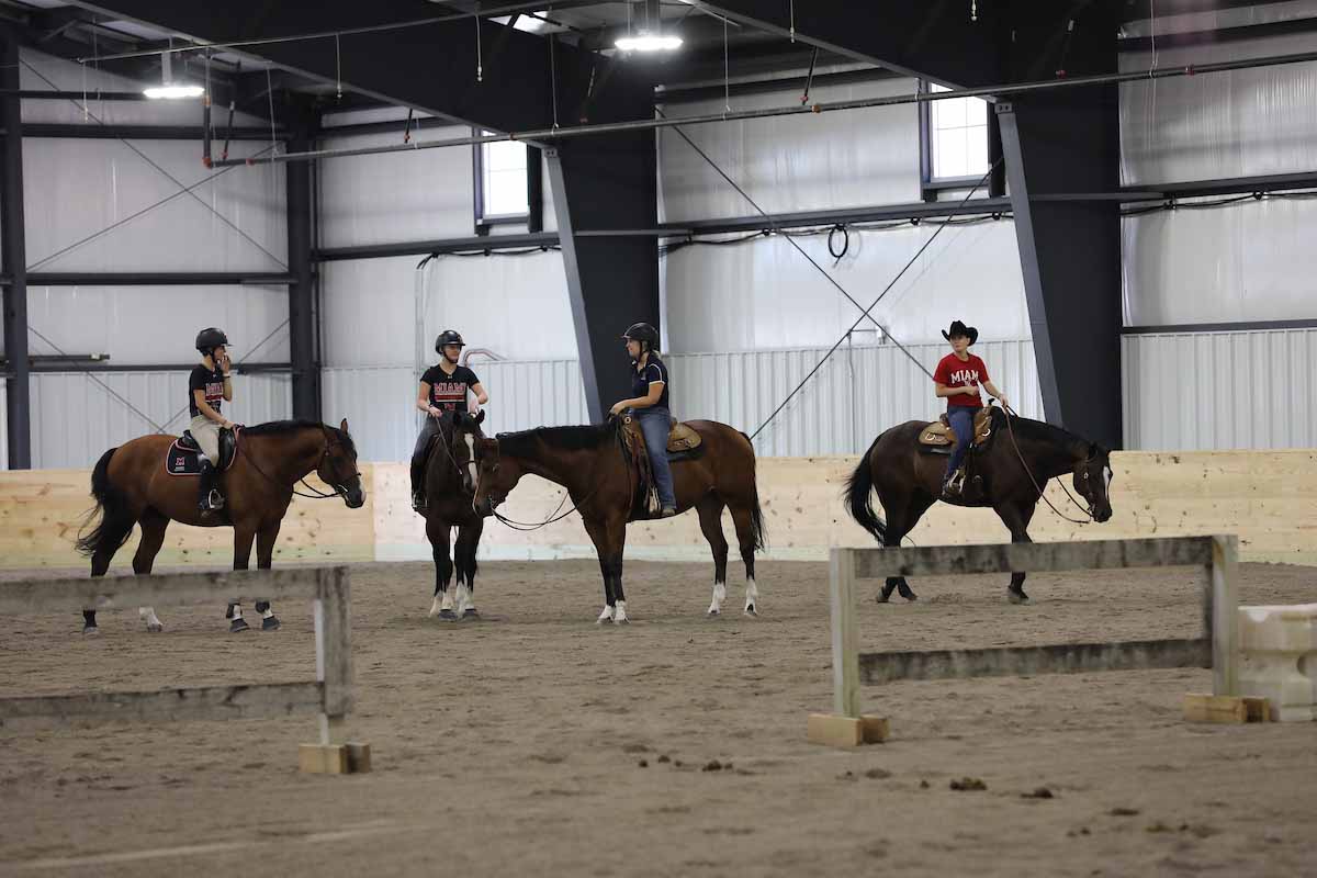 inside the equestrian center with 4 riders on horses