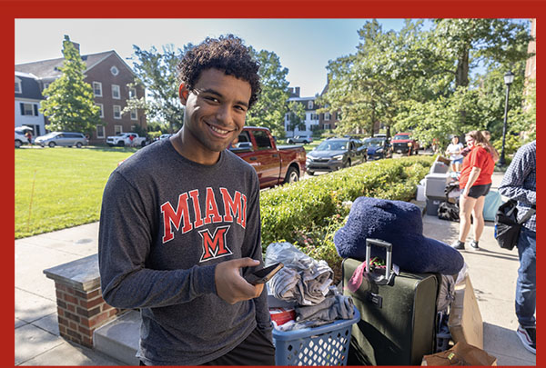 student with a smile helps with move-in near tappan hall