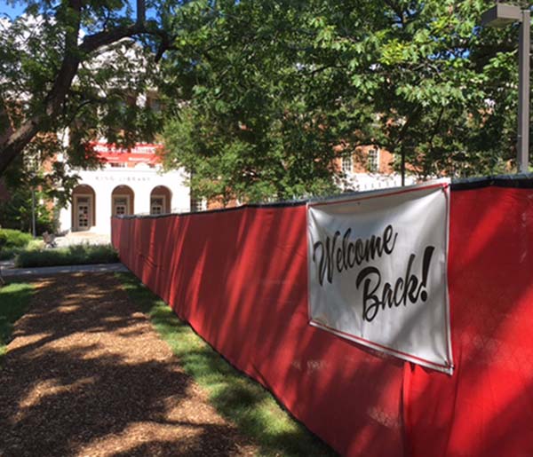 a red fence includes a welcome back sign