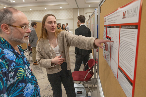 A student shows her research poster at the forum