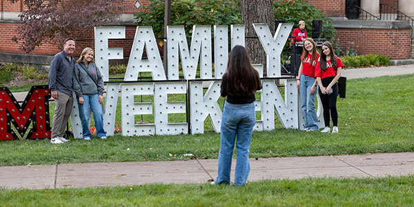 Family posing with Miami University Family Weekend sign