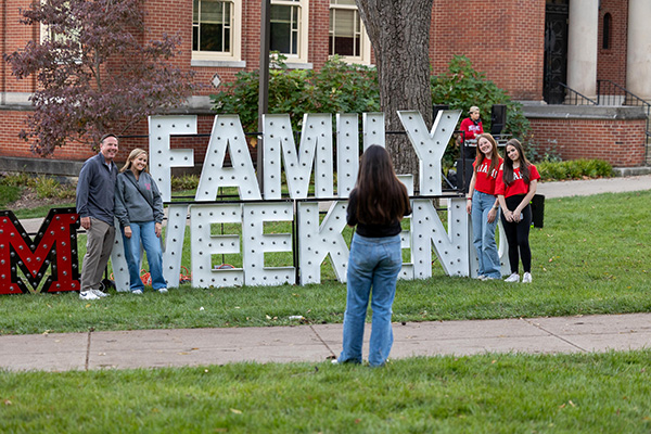 Family posing with Miami University Family Weekend sign
