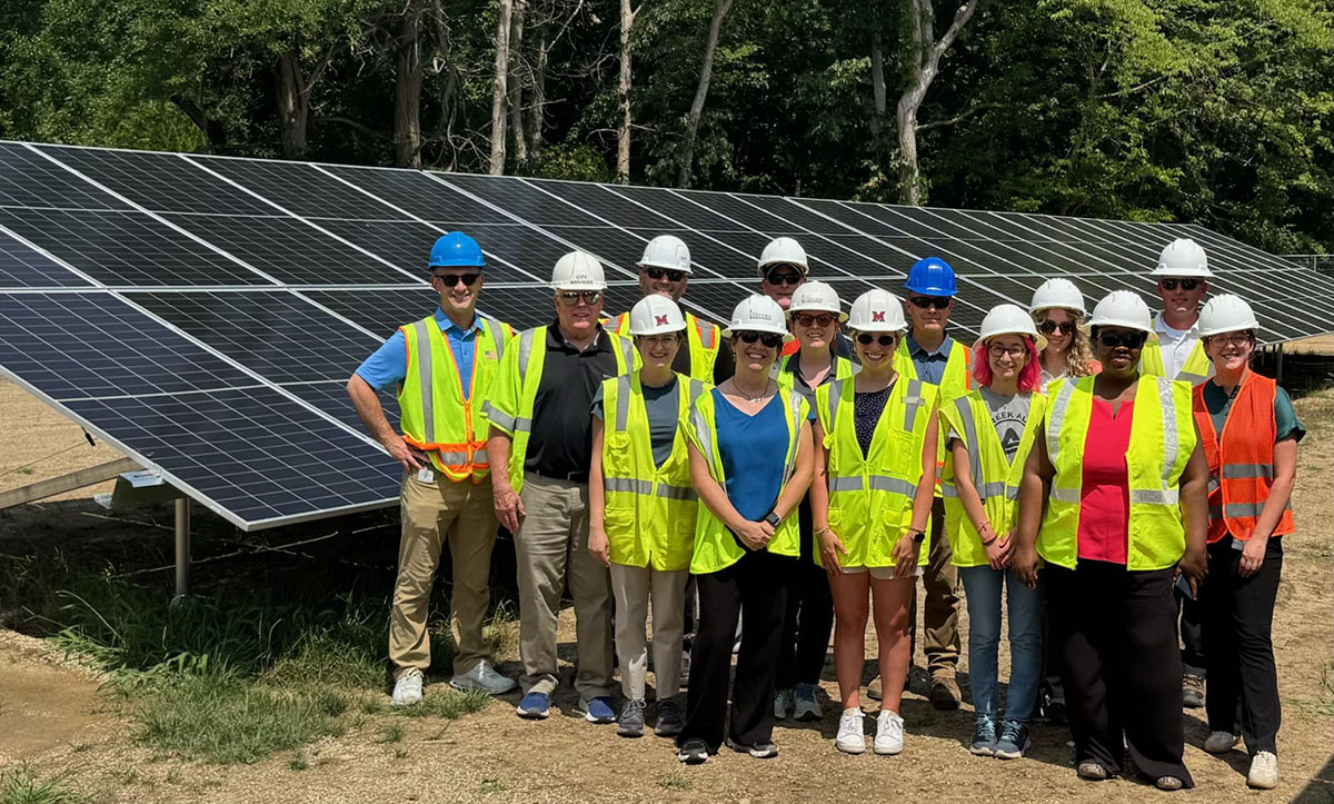 A group of Miami, City of Oxford, and City of Fairfield representatives pose near a solar panel